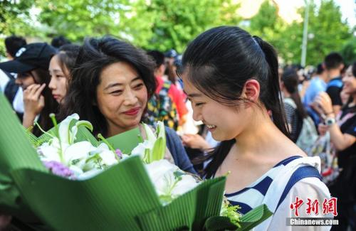 資料圖：山東濟(jì)南眾多考生手捧鮮花在家長(zhǎng)的簇?fù)硐職g快告別高考。中新社記者 張勇 攝