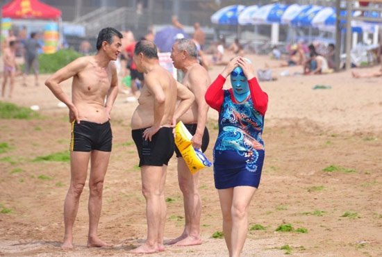 2013年7月3日，山東青島青島高溫來襲，“青島大媽”不懼滸苔，戴著“強(qiáng)盜面具”出現(xiàn)在海水浴場(chǎng)消暑降