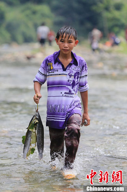 圖為7月9日，一名男孩在鬧魚節(jié)活動中抓到了兩條魚。譚凱興 攝