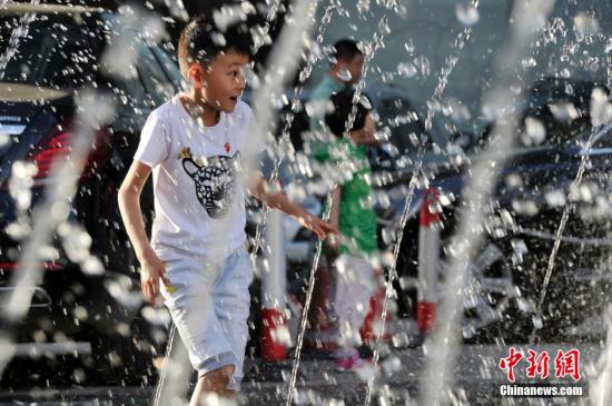 山西太原最高溫36℃,兒童在噴泉周圍戲水消暑。
