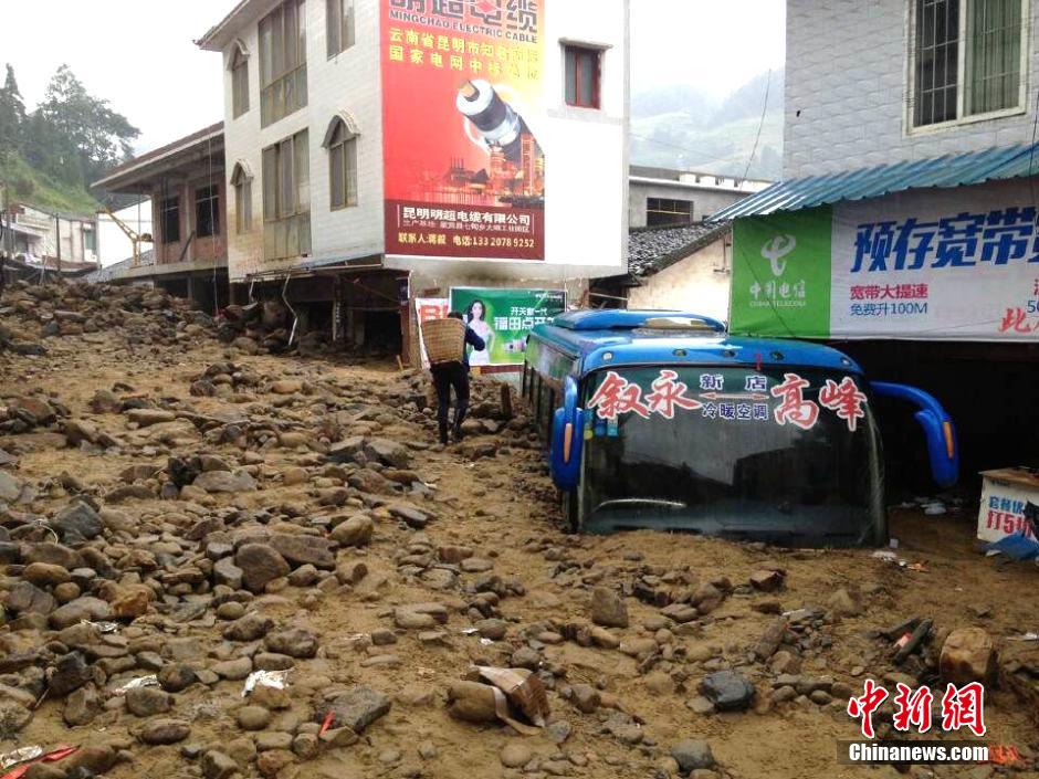 圖為山洪泥石流導(dǎo)沖進鄉(xiāng)鎮(zhèn)街道，導(dǎo)致客車被埋。