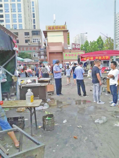昨天，執(zhí)法人員在京廣路長江路口整治“僵尸圍擋”及圍擋內(nèi)的攤販。