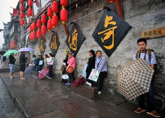 　4月29日上午11時(shí)20分，一些游客和古城當(dāng)?shù)氐木用穸阍谝粋€(gè)酒吧的屋檐下避雨。這些當(dāng)?shù)鼐用褚詾橛慰团恼罩\生，一場(chǎng)降雨讓他們的生意更加清淡。