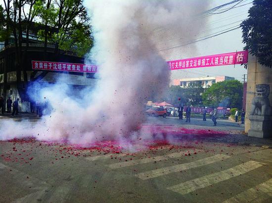 市民在普洱市主干道振興大道的金孔雀交通運(yùn)輸集團(tuán)有限公司門前燃放鞭炮，公司門前掛著“貪腐份子沈培平被查處，罪有應(yīng)得，大快人心?！钡臈l幅