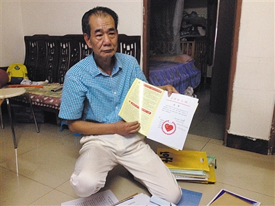 翻出一家網(wǎng)站贈予的“中國好人”證書，區(qū)少坤單膝跪在地上，“你看，我是中國好人啊?！?范春旭 攝