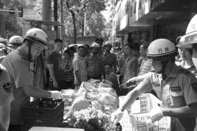 7月11日，瀏陽(yáng)市北正中路，執(zhí)法人員暫扣張海的水果。這是瀏陽(yáng)市城管局拍攝的執(zhí)法現(xiàn)場(chǎng)圖。