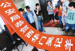 面對警方收繳的條幅，老板楊某也不好意思地用手遮擋臉