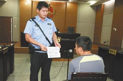 昨日庭審中，法警向趙某出示其扎完車(chē)胎后所留辱罵公司的紙條。通訊員 李秀文 攝