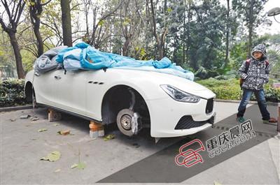昨日，停放在重慶大學(xué)B區(qū)的一輛瑪莎拉蒂豪車被架在幾塊磚頭上，車輪不翼而飛。 重慶晨報記者 胡杰 攝
