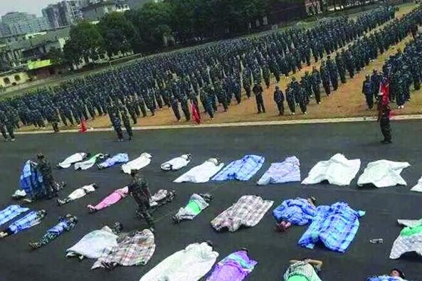 20多名女生躺在瀝青跑道上，身上嚴(yán)嚴(yán)實(shí)實(shí)地裹著棉被，接受太陽的照曬。