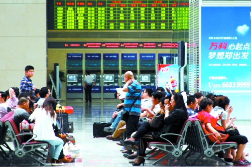 候車大廳溫度很高，一名乘客一手扇風、一手擦汗