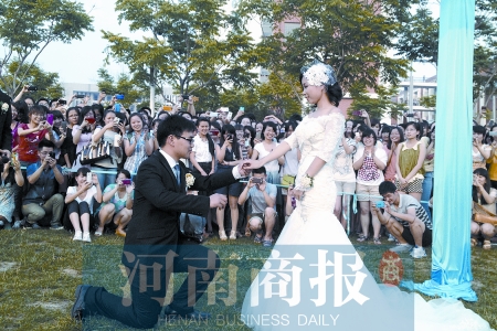 在學(xué)校操場的草坪上，兩名畢業(yè)生舉行婚禮，有同學(xué)感動地抹起眼淚