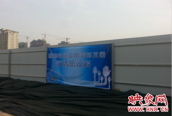 道路南側(cè)圍起了白色的圍擋，墻上標(biāo)示著“因地鐵施工帶來的不便敬請(qǐng)您諒解”的提示牌。