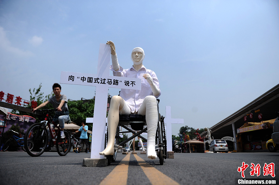 4月16日，重慶市洋人街上擺放著兩個(gè)受了傷的塑料人像“模特”，旁邊十字架上寫著向“中國式過馬路”說不