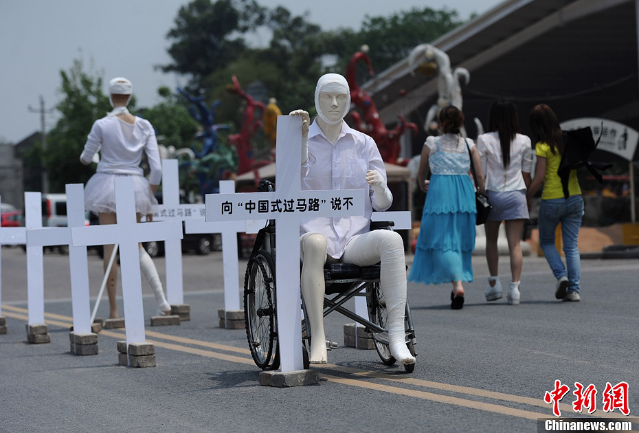 4月16日，重慶市洋人街上擺放著兩個(gè)受了傷的塑料人像“模特”，旁邊十字架上寫著向“中國式過馬路”說不
