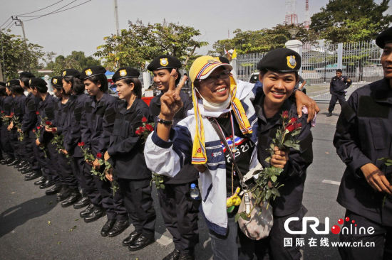 2013年12月03日,曼谷總理府與曼谷警署允許反政府示威民眾進入,雙方進入暫時“停戰(zhàn)”狀態(tài)迎接泰王生日。曼谷警察總署,女警們手持鮮花送給反政府示威民眾。圖片來源:Manish Swarup/東方IC