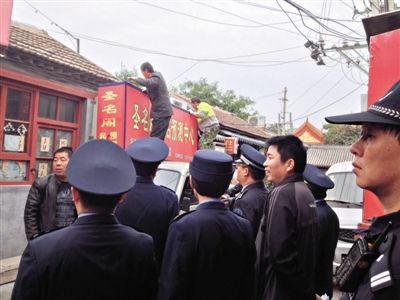 昨日下午,東城區(qū)工商、城管、公安等部門,對(duì)雍和宮附近的預(yù)測(cè)中心進(jìn)行清理整頓,站在車頂?shù)膬擅と苏鸪患摇邦A(yù)測(cè)中心”的招牌。因雍和宮、白云觀等文化景點(diǎn)外聚集大量算命先生,被媒體稱為“算命一條街”。本版攝影/新京報(bào)記者 李寧 攝
