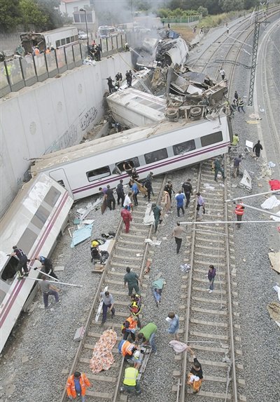 24日，救援人員在西班牙列車(chē)脫軌現(xiàn)場(chǎng)。一節(jié)車(chē)廂被強(qiáng)大的慣性?huà)伾翔F道邊的高臺(tái)。