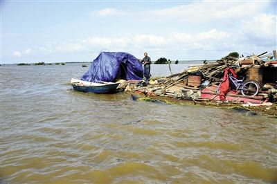 15日，因黑龍江水位上漲，一位轉移家中物資被困屋頂?shù)睦先讼蛎窬笾?。新華社發(fā)