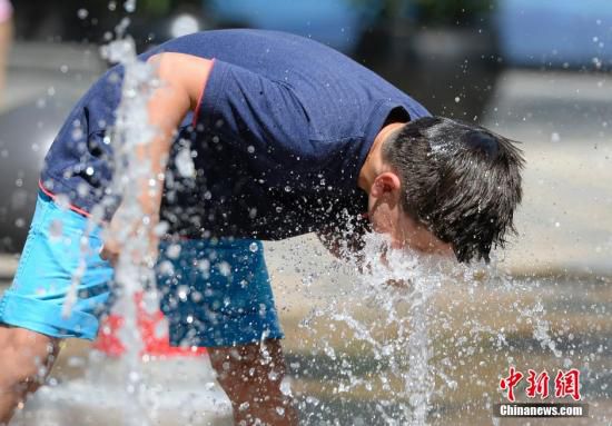 5月29日，一名小孩將頭伸向北京街頭的噴泉以降溫祛暑。