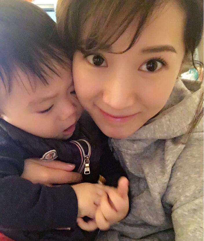 照片中李念狂吻兒子，小寶貝自顧自地玩著。
