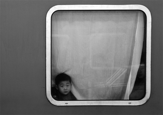 一個孩子把頭伸向窗外，他想再看送別的親人一眼