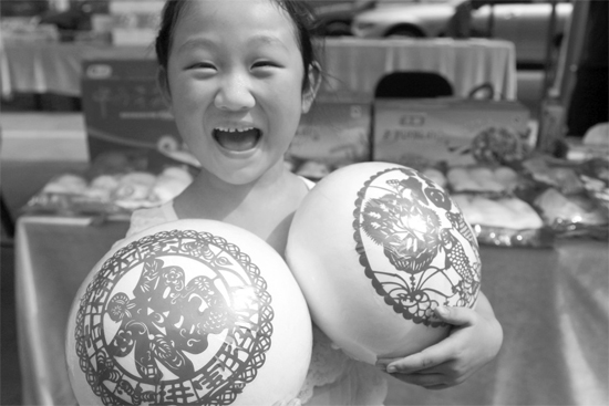 在2013河南食品安全宣傳周活動現(xiàn)場，一個小女孩抱著參展的特色大饅頭樂開了花