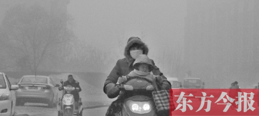 12月8日，鄭州市未來路上，一位市民帶著孩子在霧中騎行
