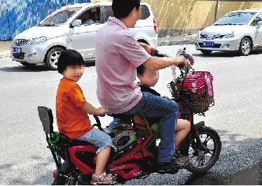 周先生騎著一輛低矮的電動(dòng)車帶著一對(duì)兒女，很不安全。