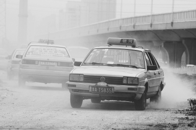 施工的道路上，車輛通過(guò)塵土飛揚(yáng)。