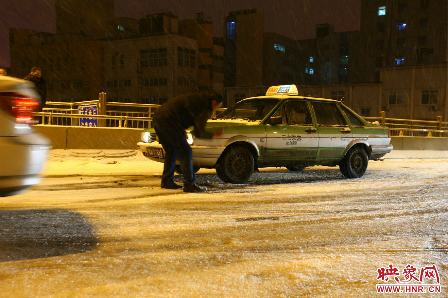 一位出租車司機(jī)在車輪前灑上雪，希望能增加輪胎的摩擦力。