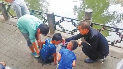 男孩被救出后，圍觀群眾幫他控水換衣服。