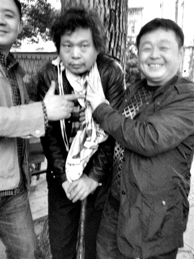 兩名接訪人員與患有癌癥的訪民段新德合影時，面帶笑容擺出勝利的手勢。