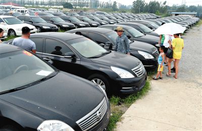昨日，市民在山東棗莊一家拍賣公司場地上查看待拍賣公車。當(dāng)日，棗莊市103輛公車公開拍賣。新華社記者