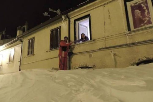 一個居民站在積雪上，可以與一名二樓鄰居在窗口握手。（來源：意大利氣象局）