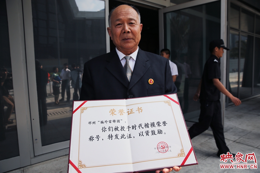 河南鄧州“編外雷鋒團”團長宋清梅向眾多記者展示中宣部授予的“時代楷?！睒s譽證書。