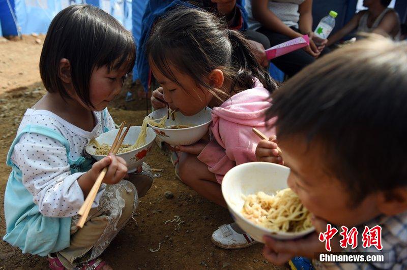 2014年8月6日，云南魯?shù)辇堫^山災(zāi)區(qū)，兒童在帳篷外吃飯。