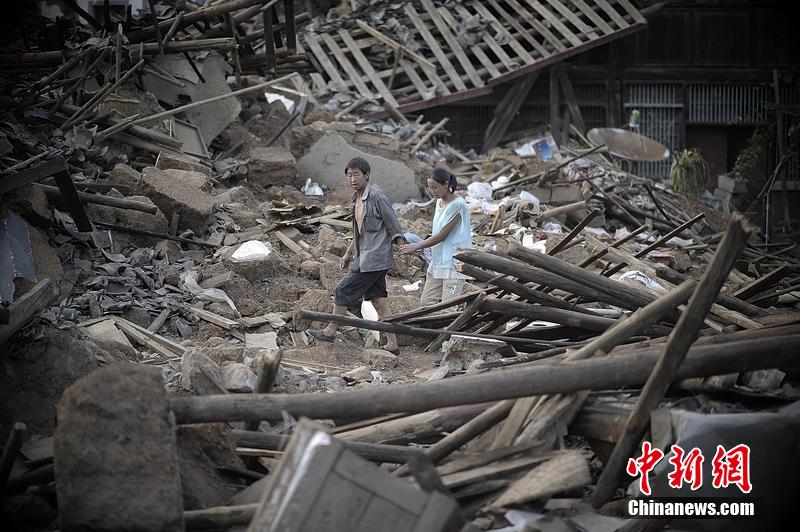 2014年8月5日，云南昭通龍頭山鎮(zhèn)老街，一對夫妻從居住房屋的廢墟中走過。