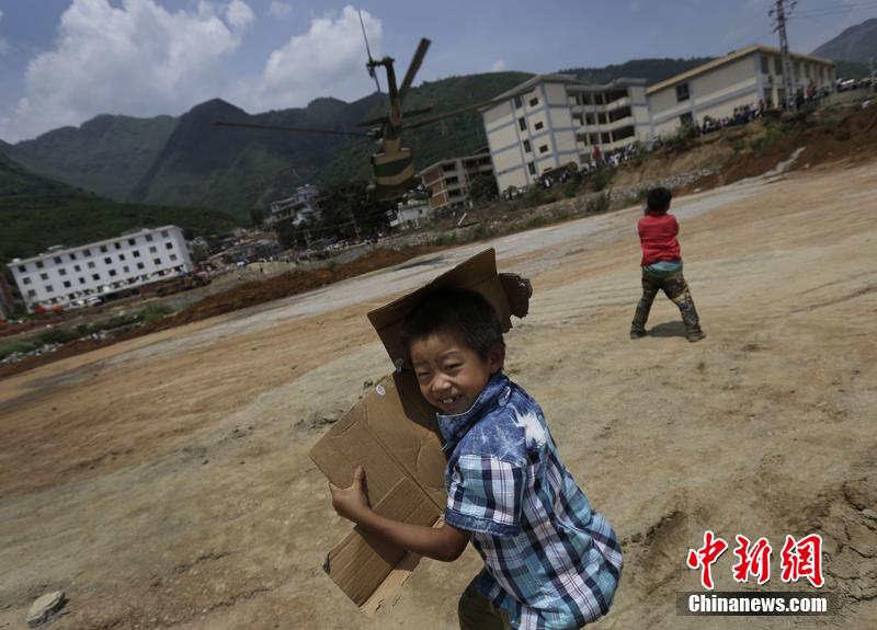 云南省昭通市魯?shù)榭h發(fā)生6.5級地震。幾個孩子在直升機(jī)降落的平地上玩耍。