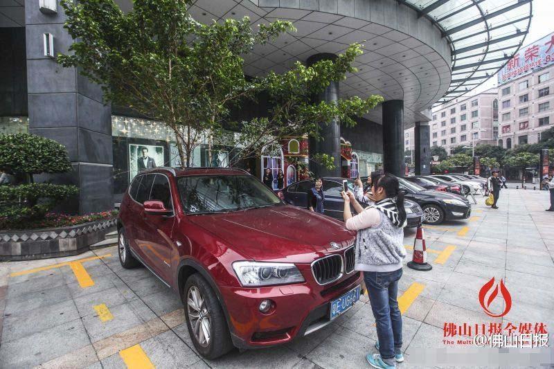 一輛停在停車位上的寶馬轎車，被墜落的樹枝砸中，樹枝徑直插入車內(nèi)，現(xiàn)場引發(fā)不少市民圍觀拍照。