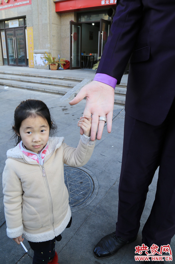 巨人“張歡”牽著一名漂亮的小女孩，兩人的手大小對比非常明顯。