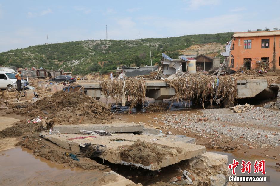 圖為洪水過(guò)后，坍塌的橋梁上遺落大量雜草。