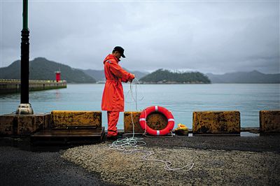 7月6日，韓國珍島，一名海岸警察在港口系救生圈。4月，客輪在珍島近海發(fā)生沉船事故后，仍有11人下落不明。