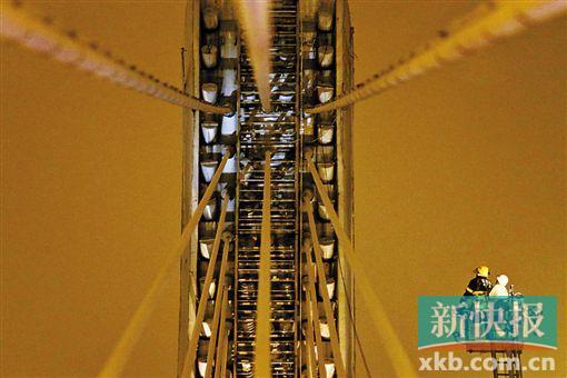 截至今日零時(shí)，男子仍未有下橋舉動(dòng)。圖為公安和消防人員乘消防云梯在高空上和男子交談。