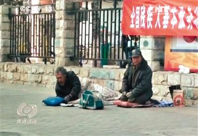 工人體育場(chǎng)北路，兩位乞討者路邊乞討，并輪流扮成“病人”（躺地者）。 央視截圖