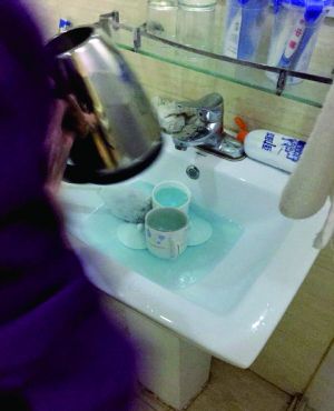 酒店服務(wù)員用潔廁液刷燒水壺和茶杯。