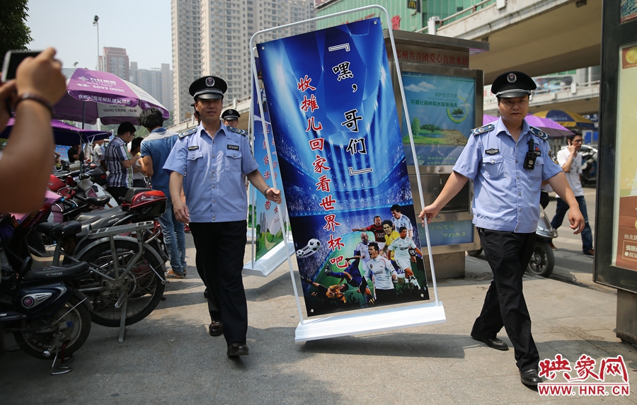 7月2日上午，鄭州市紫荊山地鐵站出入口，執(zhí)法人員抬著寫有勸導(dǎo)語的宣傳板，前往占道經(jīng)營(yíng)攤位“圍觀執(zhí)法”